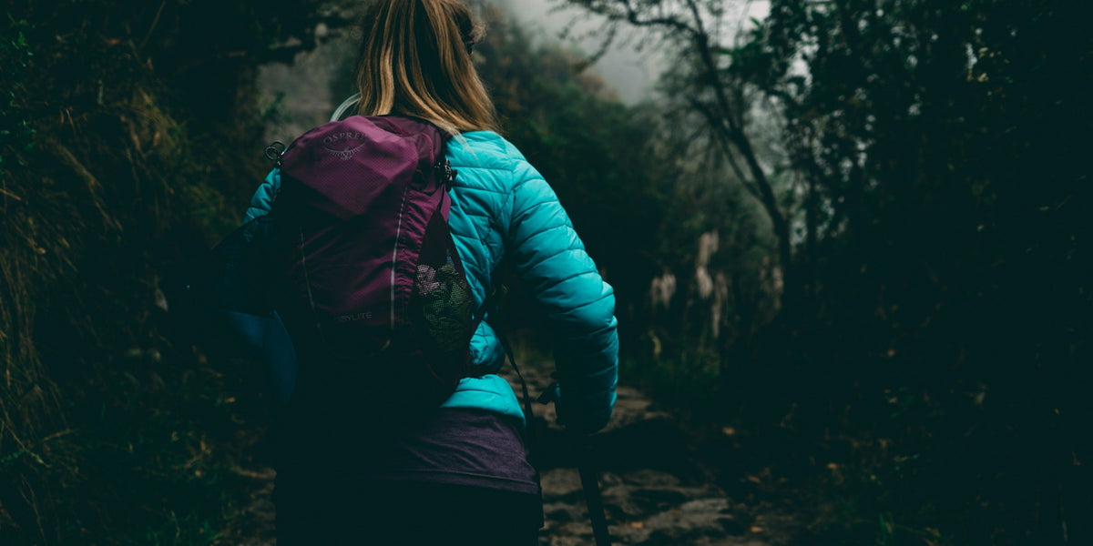 Hiker in a puffer jacket walking a forest path