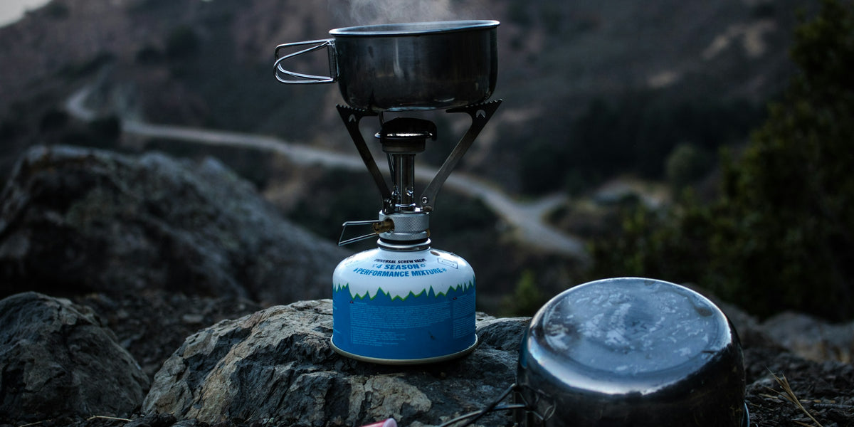 Camping gas stove and cooking pot on a rock