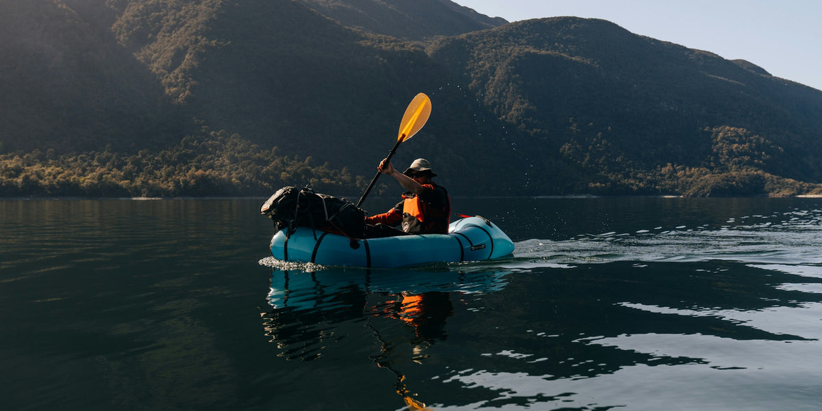 Packraft with a paddler and a dog on a mountain lake