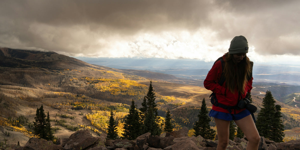 Hiker in a beanie looking over an autumn mountain landscape