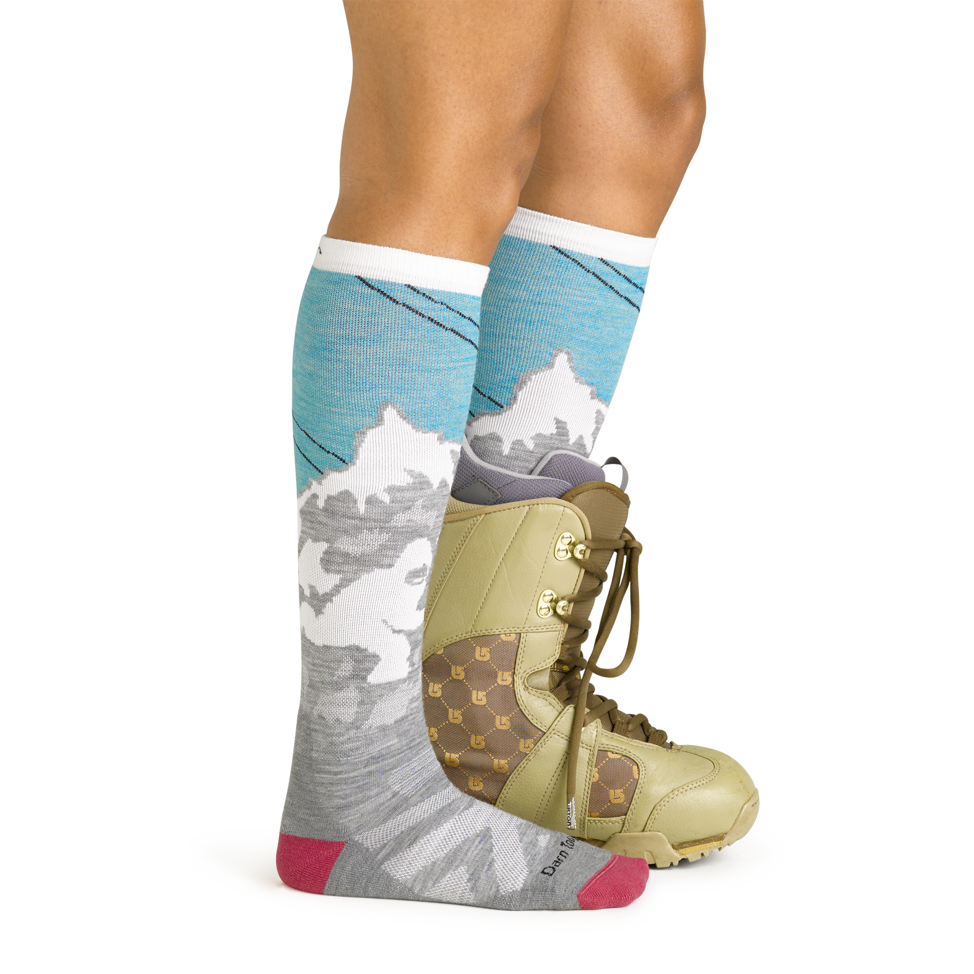 Side studio shot of model wearing the Darn Tough Yeti over-the-calf sock in Aqua with a green snowboard boot on the left foot