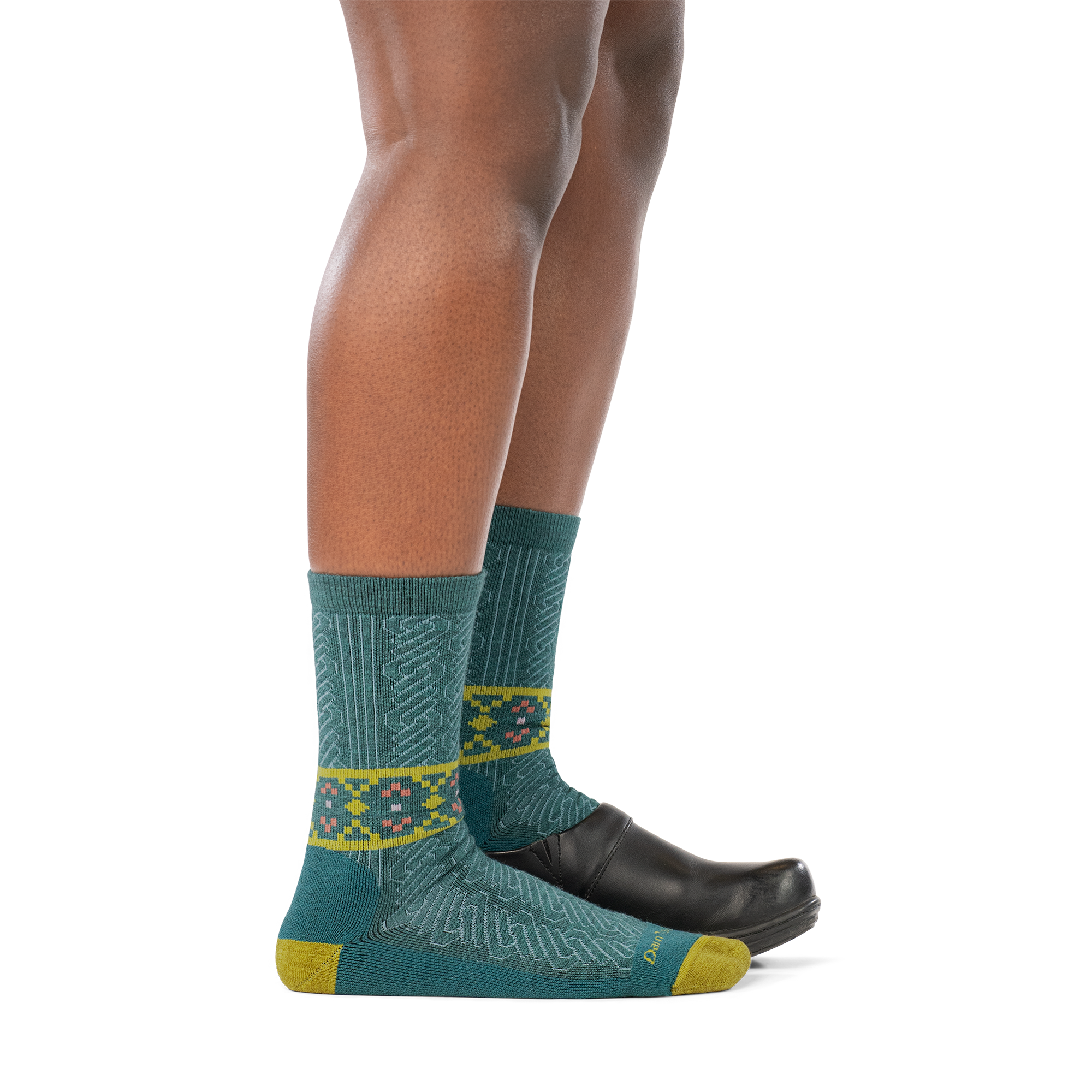 Model wearing a clog on the back foot and the Darn Tough Nordic Twist Crew sock in Teal on the front foot, side profile