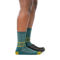 Model wearing a clog on the back foot and the Darn Tough Nordic Twist Crew sock in Teal on the front foot, side profile