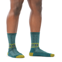 Model barefoot in a staggered stance wearing the Darn Tough Nordic Twist Crew sock in Teal, side profile