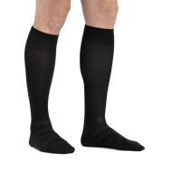 Man standing barefoot wearing the Darn Tough RFL Over-the-Calf Ultra-Lightweight Ski & Snowboard Sock in Black