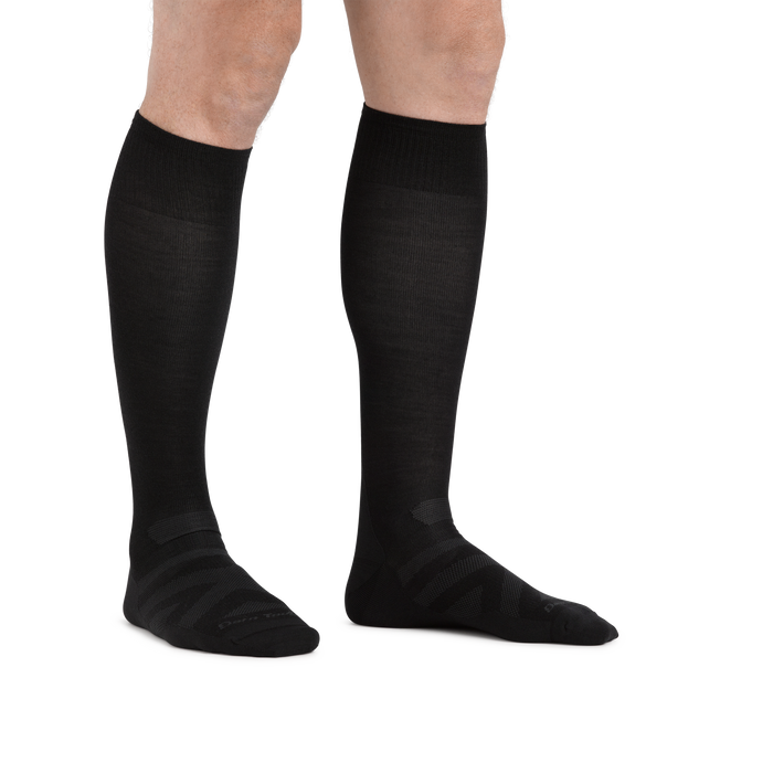 Man standing barefoot wearing the Darn Tough RFL Over-the-Calf Ultra-Lightweight Ski & Snowboard Sock in Black