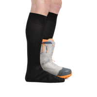 Man wearing the Darn Tough RFL Over-the-Calf Ultra-Lightweight sock in Black with the back foot in a snowboard boot